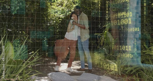 Embracing couple standing on backyard patio, holding white flower near binary wire-grid overlay