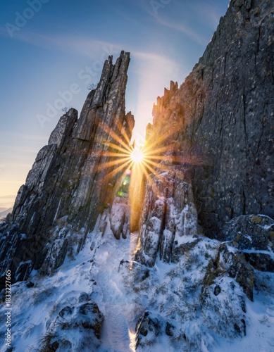 Dramatic Mountain Landscape with Snow and Sunlight Burst at Dusk