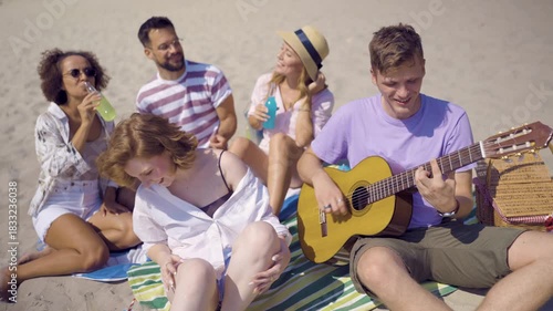 A joyful group of friends celebrating together at a beach party during sunset.