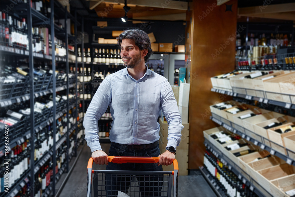 Naklejka premium A man is pushing a shopping cart in a wine store browsing