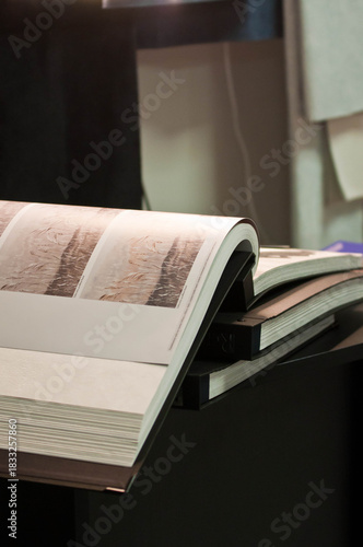 A display of ceramic tile samples in various neutral tones arranged in a showroom. The collection includes stone-texture and matte-finish tiles, creating a professional interior design workspace setti