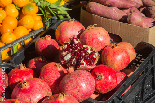 At a market stall:Fruits of pomegranates-one split open to reveal clusters of seeds with sarcotesta on the inside-symbolic, religious holy fruit in many cultures as Iran or the Ancient Greece