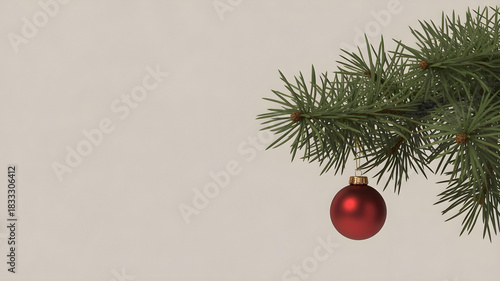 A fir branch with a single red Christmas bauble hanging from it, against a plain light background.