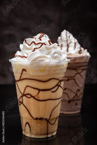 Vanilla milkshake with chocolate syrup in clear glass on dark background.