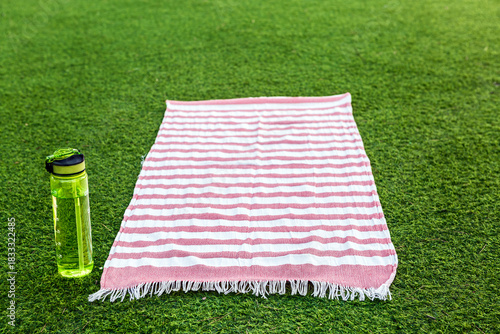 Striped towel on grass with water bottle ready for a summer picnic