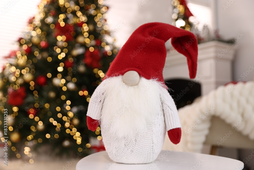Fototapeta premium Funny Christmas gnome on white table in decorated room, closeup