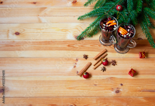 Glasses of mulled wine, christmas balls, gifts and spices on wooden background. Top view with copy space.