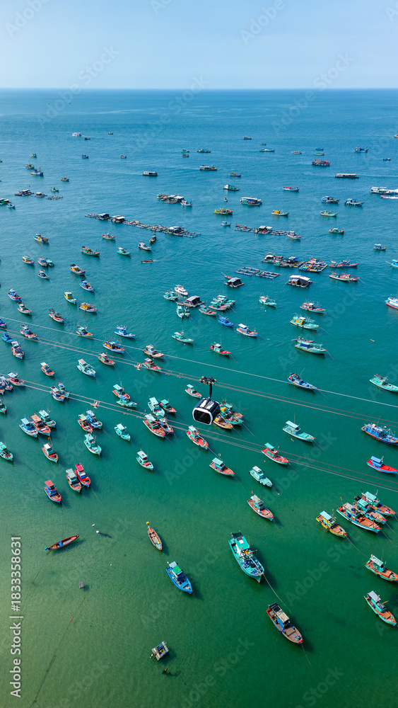 Fototapeta premium Aerial view of colorful fishing boats anchored near coastal fishing village on Phu Quoc Island, Vietnam. 