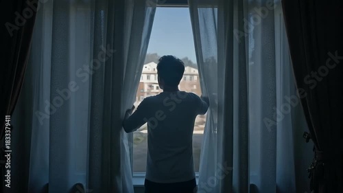 Contemplative man looking out window, seeking inspiration and new beginnings, bathed in gentle light of dawn, evoking hope and fresh starts