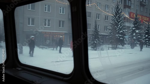 Orange snowplow truck clearing winter street with New Year decorations