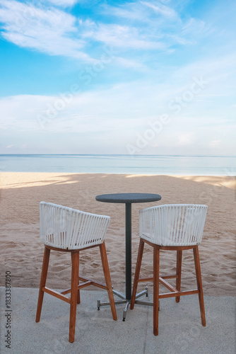 two long legs stools with one black circle table on beach.