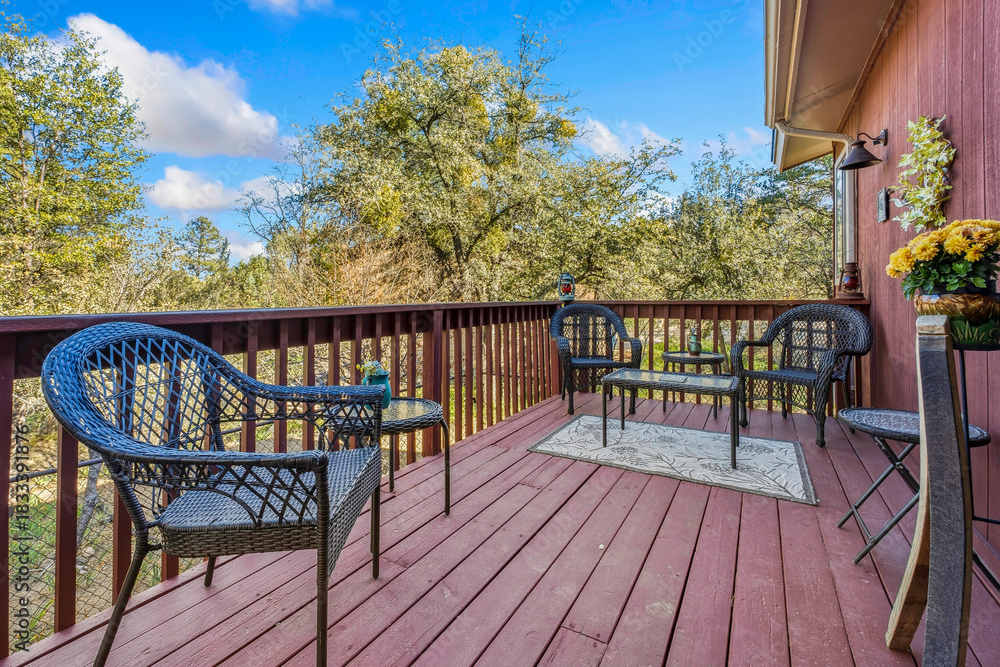 Naklejka premium Sunny Outdoor Retreat, Bright Outdoor Corner Decorated With Wicker Furniture And Scenic Treetops