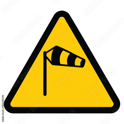 A yellow triangular warning sign with a black border featuring a black windsock icon indicating strong winds or a wind sensitive area such as an airport.
