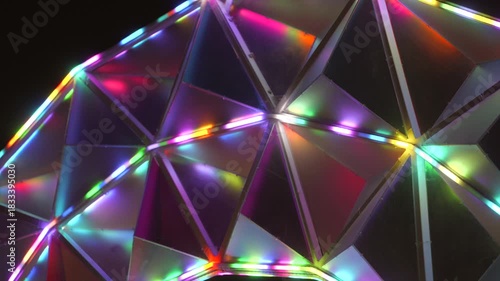 This close up video shows a silver geometric structure, changing colors.