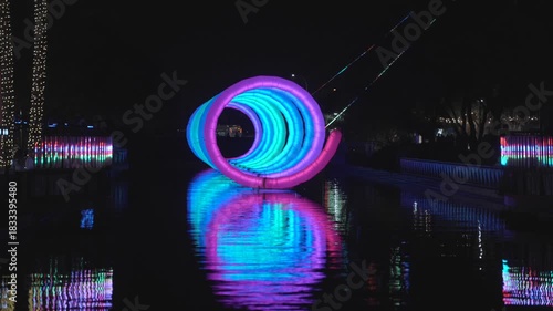 This video shows a colorful spiral on canal water at night as the changing colors reflect in the water.