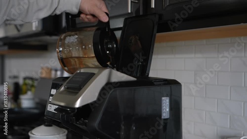 man pouring water into coffee machine reservoir