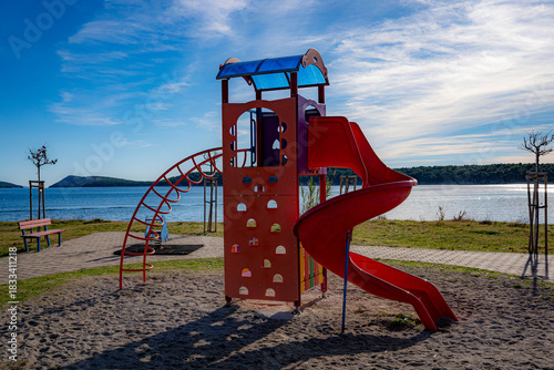 Fototapeta Naklejka Na Ścianę i Meble -  children's playground by the sea, red color, rab, croatia, mediterranean, clear, few clouds