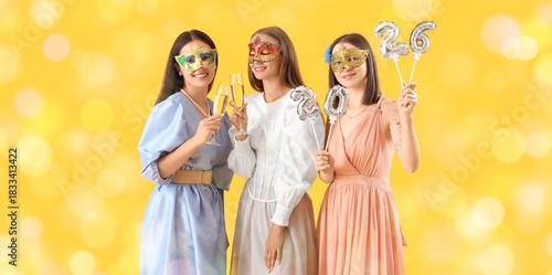 Beautiful young women in carnival masks, with champagne and balloons celebrat...