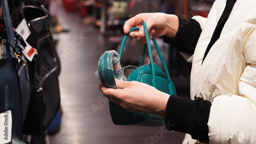 Woman hands making a shopping decision while comparing trendy bags in store.