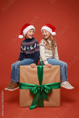 Joyful Kids in Santa Hats on Christmas Gift