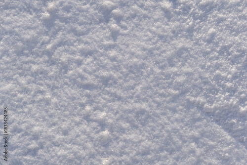 Top view photo of snow on the ground in the sunny winter morning. Winter white pure clean snow background texture with soft snowflakes on cold day.