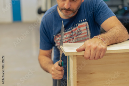 A young craftsman restores a caravan in a hangar.