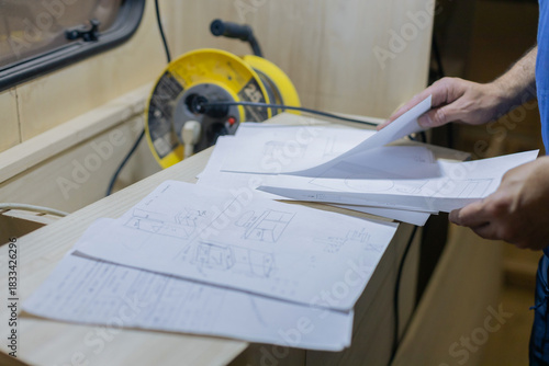 A young craftsman restores a caravan in a hangar.