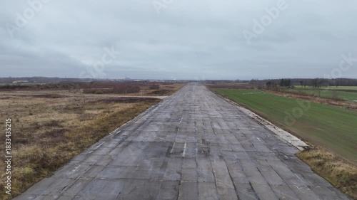A deserted concrete runway of a former Soviet military airbase in Kedainiai, Lithuania. Overcast sky, rural fields, and decaying aviation infrastructure