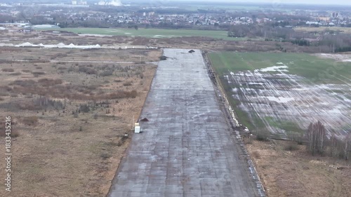 A deserted concrete runway of a former Soviet military airbase in Kedainiai, Lithuania. Overcast sky, rural fields, and decaying aviation infrastructure