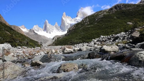 Fitzroy mountain in Patagonia with sharp granite peaks rugged terrain drifting clouds clear sky remote wilderness glacial valley rocky landscape natural environment and panoramic daylight view scenery