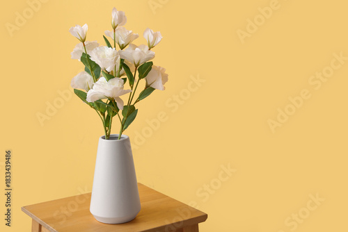 Wallpaper Mural Vase with artificial eustoma flowers on table against yellow background Torontodigital.ca