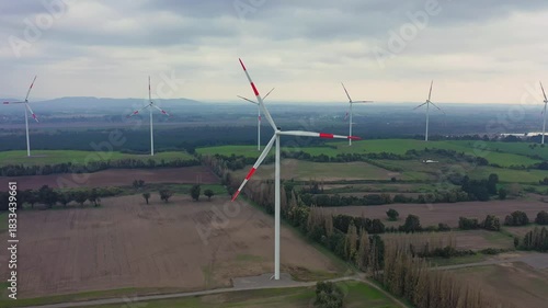 Wind turbine stands tall over lush green fields in rural area during daytime