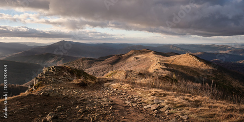 Fototapeta Naklejka Na Ścianę i Meble -  Warm evening light over a mountain ridge and rocky hiking trail in a remote national park, perfect for travel, adventure, hiking and nature landscape concepts.