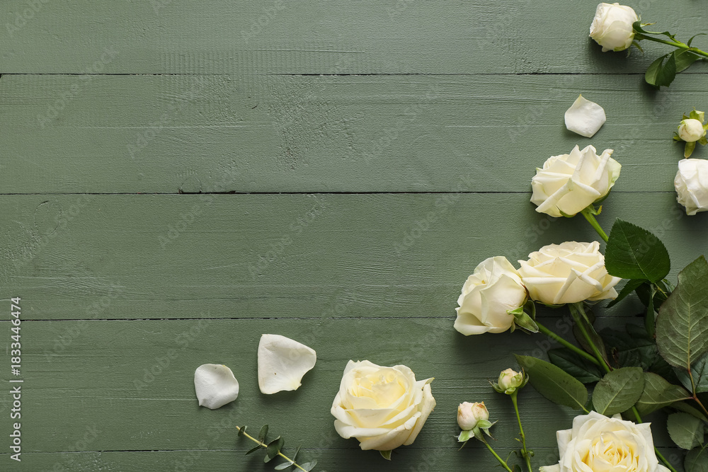 Naklejka premium Beautiful white roses and eucalyptus branch on green wooden background