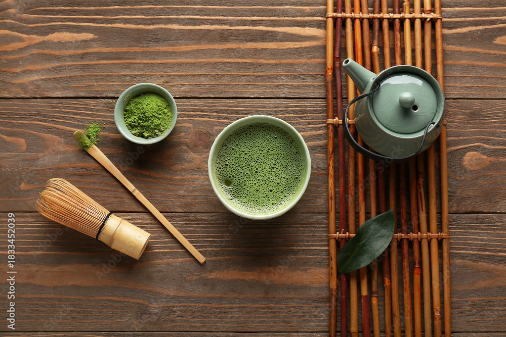 Naklejka premium Bowl of fresh matcha tea with powder, chasen, chashaku and teapot on wooden background