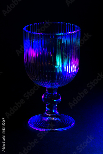 Colorful Lit Glass Goblet with Intricate Details in Dark Ambiance
