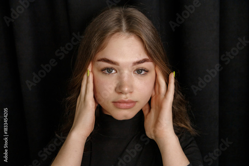 Young woman with flawless skin showcasing expertly shaped eyebrows and elegant eyelashes