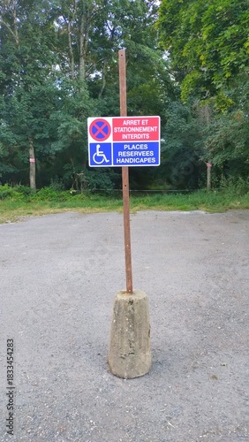 Panneau de stationnement pour personnes handicapées sur un parking en bordure de forêt