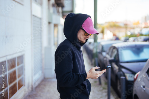 Casual urban figure inspecting rideshare application near parked vehicles