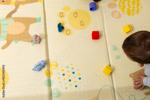 Baby playing with colorful toys on floor mat