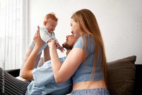 Couple enjoys time with their baby in a cozy living room during the day while sharing smiles and laughter