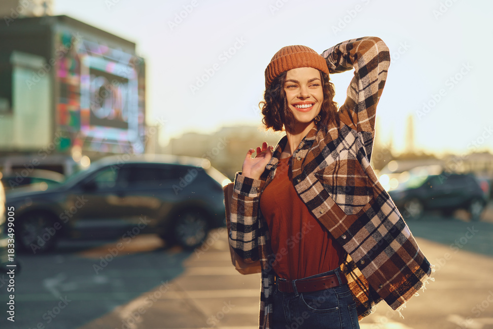 Fototapeta premium Woman smile portrait in urban street at golden hour glow, candid lifestyle capture with authenticity and joyful expression, beanie and plaid coat, mindful living and emotional storytelling vibe.