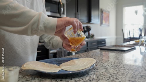 man spreading pineapple jam on tortillas for breakfast