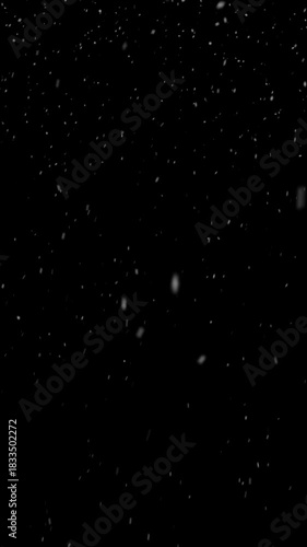 Realistic snow falls across the screen on black background, falling snowflake particle effects for christmas holiday celebration, overlay natural winter storm weather vertical backdrop