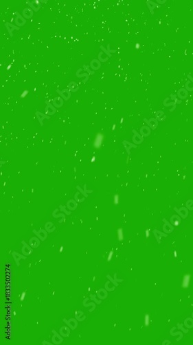 Realistic snow falls across the screen on green screen background, falling snowflake particle effects for christmas holiday celebration, overlay natural winter storm weather vertical backdrop