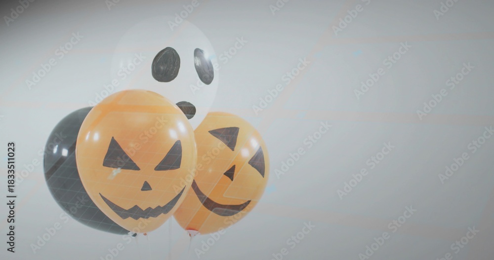 Fototapeta premium Floating cluster of four Halloween balloons showing jack-o'-lantern and ghost faces in studio