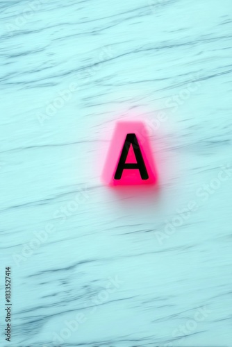 A pink letter A on a light blue marble surface. The letter is glowing.  The background is a marble texture.