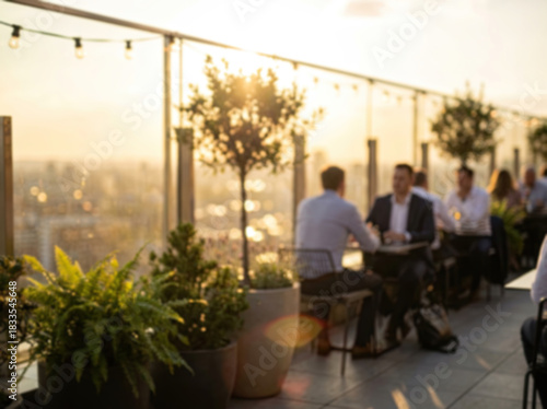 Blurred people relaxing at a rooftop bar with a city view at sunset