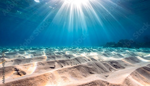 Underwater sunbeams illuminate sandy seabed