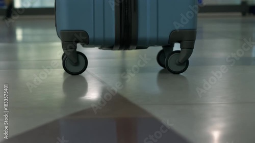 closeup sided view of rolling a suitcase wheel on airport floor